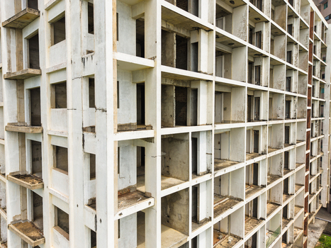 Aerial view of the geometric grid pattern of an unfinished concrete apartment building with empty window frames and weathered walls in Galle Southern Province Sri Lanka. Aerial view of the geometric grid pattern of an unfinished concrete apartment building with empty window frames and weathered walls in Galle Southern Province Sri Lanka.