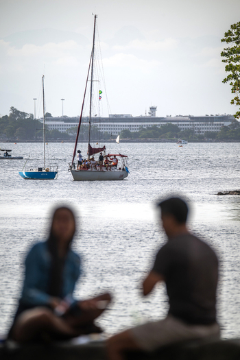 Rio de Janeiro Brazil 14 June 2026 View of sailboats on Guanabara Bay with silhouettes of people sitting at Mureta da Urca in the foreground.