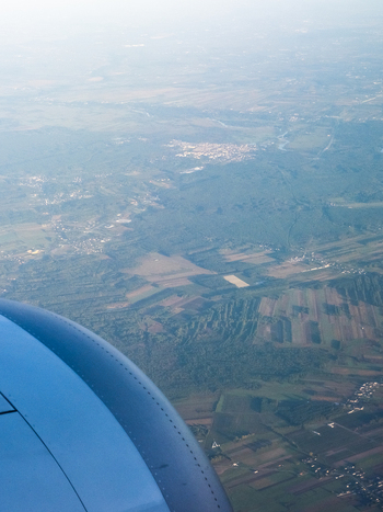 Aerial view of a patchwork of fields and forests fading into the misty horizon seen from an airplane window Warsaw Masovian Voivodeship Poland. Aerial view of a patchwork of fields and forests fading into the misty horizon seen from an airplane window Warsaw Masovian Voivodeship Poland.