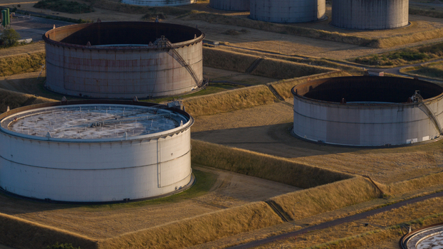 Aerial view of Tanklager oil storage tanks surrounded by grassy embankments in the golden hour light in Hunxe North Rhine Westphalia Germany.