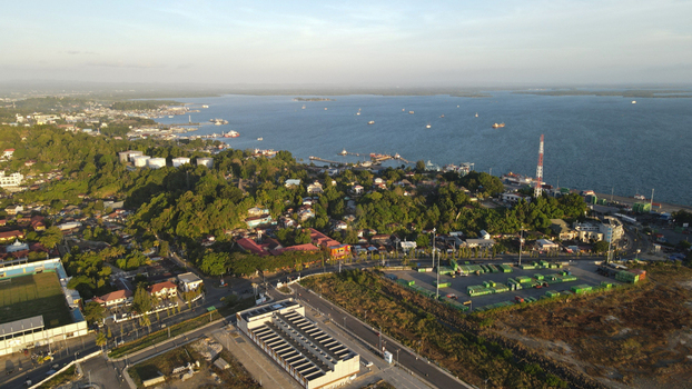 Aerial view of the coastal city of Sorong featuring the port area industrial facilities residential neighborhoods and a stadium nestled among hills in Sorong Southwest Papua Indonesia. Aerial view of the coastal city of Sorong featuring the port area industrial facilities residential neighborhoods and a stadium nestled among hills in Sorong Southwest Papua Indonesia.