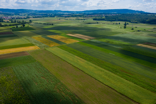 Aerial view of patchwork agricultural fields and rolling hills under a cloudy sky near Nuremberg Bavaria Germany.