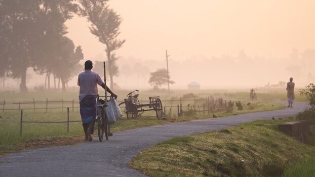 View of a man walking with a bicycle on a misty road Bangladesh.