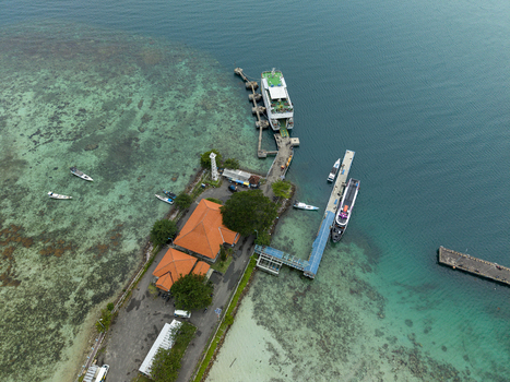 Aerial view of the ferry harbor with turquoise waters meeting the shore boats docked and a red roofed building standing out Karimunjawa Jawa Tengah Indonesia. Aerial view of the ferry harbor with turquoise waters meeting the shore boats docked and a red roofed building standing out Karimunjawa Jawa Tengah Indonesia.