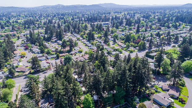 Aerial view of Northeast Glisan Street and surrounding residential neighborhood with lush evergreen trees and suburban houses under a clear sky in Portland Oregon United States. Aerial view of Northeast Glisan Street and surrounding residential neighborhood with lush evergreen trees and suburban houses under a clear sky in Portland Oregon United States.