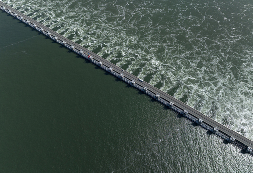 Aerial view of the Eastern Scheldt Storm Surge Barrier with turbulent water and road traffic in Vrouwenpolder Zeeland Netherlands. Aerial view of the Eastern Scheldt Storm Surge Barrier with turbulent water and road traffic in Vrouwenpolder Zeeland Netherlands.