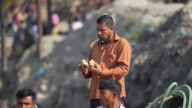View of a man eating a banana and bread in Dhaka Bangladesh.
