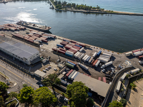 Aerial view of the Rio Ozama port area with shipping containers industrial warehouses and a cargo ship docked along the waterfront in Santo Domingo Santo Domingo Dominican Republic.