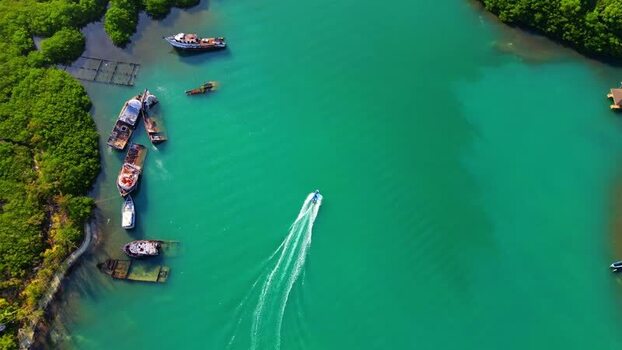 Aerial view of a boat cruising past shipwrecks in a bay Honduras.