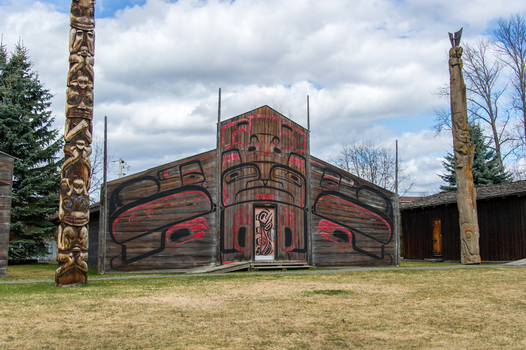 View of the traditional longhouse and carved totem poles at Ksan Historical Village in Ksan British Columbia Canada. View of the traditional longhouse and carved totem poles at Ksan Historical Village in Ksan British Columbia Canada.