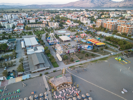 Aerial view of Luna Park Hasanaj amusement park with rides and ferris wheel located near the sandy beach and town buildings in Velipoje Shkoder County Albania.