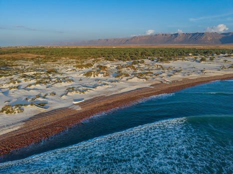 Aerial view of the stark contrast between the turquoise waves and the sandy shores near the distant mountains Kadrihnitin Socotra Yemen. Aerial view of the stark contrast between the turquoise waves and the sandy shores near the distant mountains Kadrihnitin Socotra Yemen.