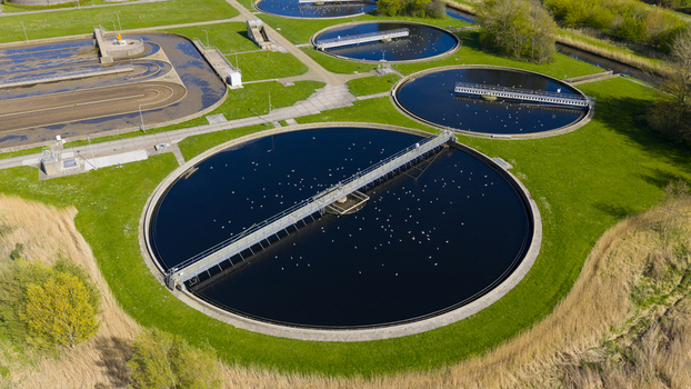 Aerial view of RWZI Geestmerambacht wastewater treatment plant with circular tanks and seagulls on the water surface surrounded by green fields Netherlands. Aerial view of RWZI Geestmerambacht wastewater treatment plant with circular tanks and seagulls on the water surface surrounded by green fields Netherlands.