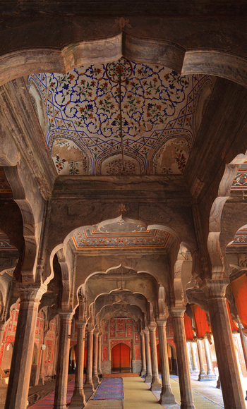 View of the intricate arches and detailed floral ceiling paintings inside the historic Shahi Mosque in Chiniot Punjab Pakistan.