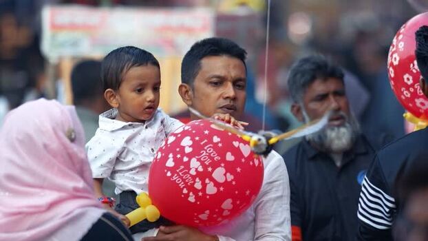 View of a man holding a child and a red balloon Bangladesh. View of a man holding a child and a red balloon Bangladesh.