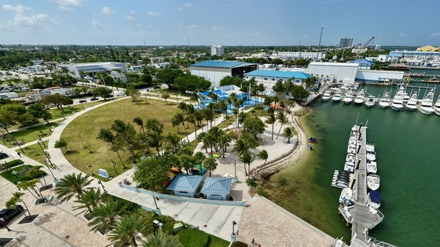 Aerial view of Peanut Island featuring a marina with docked boats lush palm trees and a green park area under a clear sky in Palm Beach County Florida United States.