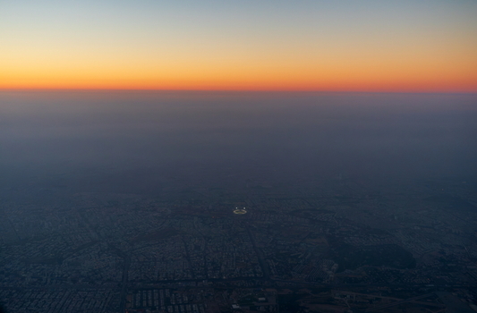 Aerial view of the sprawling urban landscape of Karachi at dusk with a glowing horizon and city lights illuminating the streets in Karachi Sindh Pakistan.
