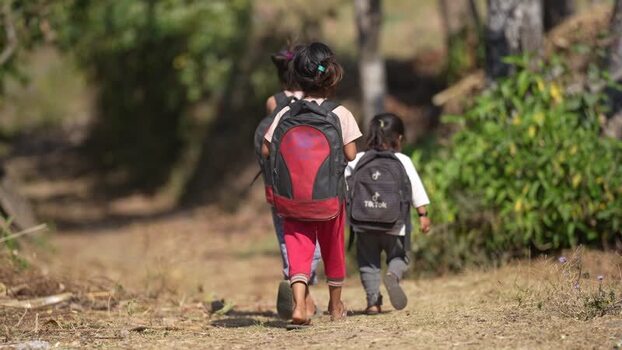 View of children walking on a rural path with backpacks Nepal.