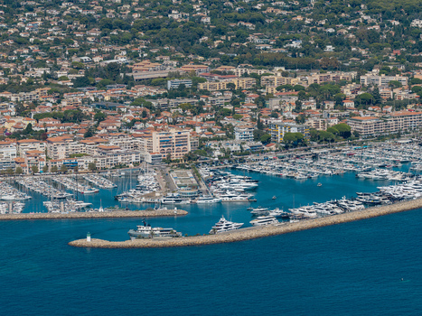 Aerial view of the marina in Antibes filled with luxury yachts and boats protected by stone breakwaters with the coastal town in the background in Antibes Provence Alpes Cote d Azur France. Aerial view of the marina in Antibes filled with luxury yachts and boats protected by stone breakwaters with the coastal town in the background in Antibes Provence Alpes Cote d Azur France.