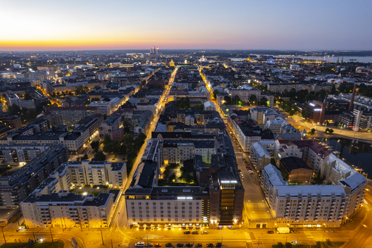Aerial view of the illuminated cityscape at dusk featuring dense urban blocks historic architecture and glowing streets in Helsinki Uusimaa Finland.