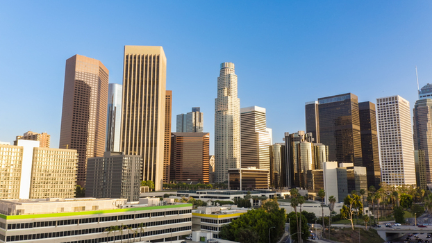 Aerial view of the Los Angeles skyline featuring modern skyscrapers and office buildings under a clear blue sky in Los Angeles California United States.