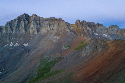 Aerial view of Mount Sneffels in the San Juan Mountains featuring rugged rocky peaks steep slopes with patches of snow and dramatic alpine terrain in Ouray County Colorado United States. Aerial view of Mount Sneffels in the San Juan Mountains featuring rugged rocky peaks steep slopes with patches of snow and dramatic alpine terrain in Ouray County Colorado United States.