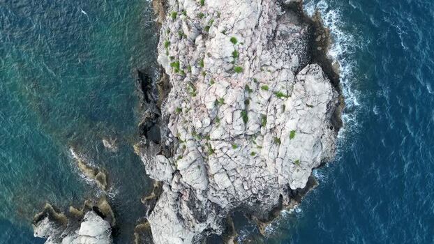 Aerial view of a rocky islet surrounded by blue sea Italy.