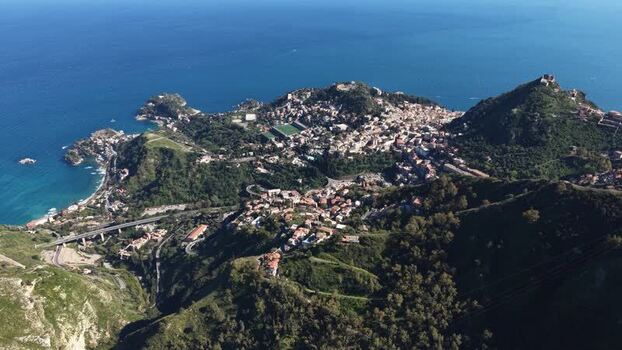 Aerial view of Taormina town on a cliff by the sea Italy.