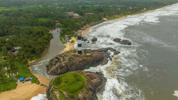 Aerial view of Kapu Light House standing on a rocky outcrop surrounded by the Arabian Sea lush palm trees and sandy beaches in Udupi Karnataka India.