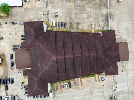 Aerial view of a large building with a dark brown roof surrounded by grey pavement and many dark vehicles Umuahia Abia Nigeria. Aerial view of a large building with a dark brown roof surrounded by grey pavement and many dark vehicles Umuahia Abia Nigeria.