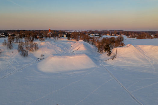 Aerial view of the snow covered Kernave Archaeological Site mounds during golden hour with a church in the background Kernave Vilnius County Lithuania.