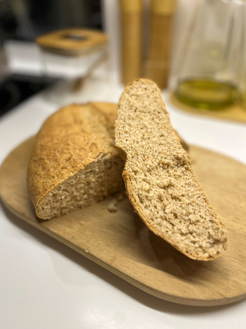 View of a freshly baked loaf of sliced whole wheat bread with a golden crust on a wooden cutting board in a modern kitchen Beylikduzu Istanbul Turkiye. View of a freshly baked loaf of sliced whole wheat bread with a golden crust on a wooden cutting board in a modern kitchen Beylikduzu Istanbul Turkiye.