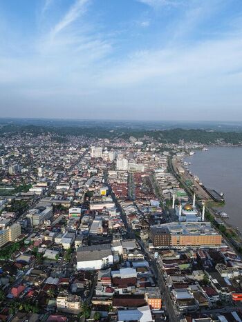 Aerial view of Samarinda city featuring the Masjid Raya Darussalam with its golden dome along the Mahakam River surrounded by dense urban rooftops in Samarinda Kalimantan Timur Indonesia. Aerial view of Samarinda city featuring the Masjid Raya Darussalam with its golden dome along the Mahakam River surrounded by dense urban rooftops in Samarinda Kalimantan Timur Indonesia.