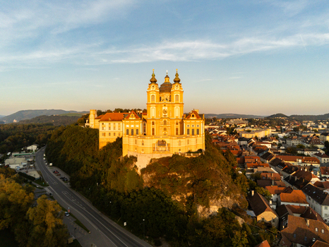 Aerial view of Melk Abbey a historic Benedictine abbey perched on a rocky outcrop overlooking the town bathed in the warm light of the golden hour. Melk Niederosterreich Austria. Aerial view of Melk Abbey a historic Benedictine abbey perched on a rocky outcrop overlooking the town bathed in the warm light of the golden hour. Melk Niederosterreich Austria.
