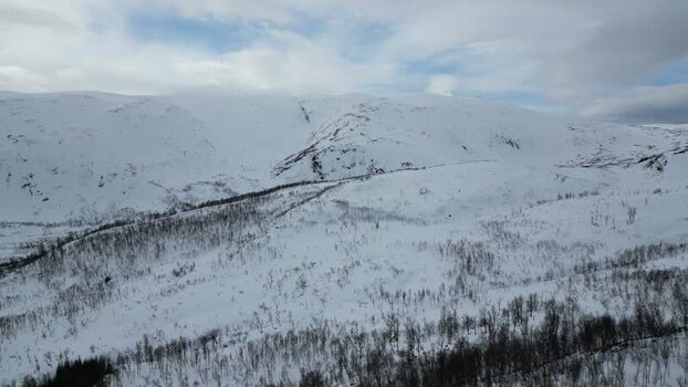 Aerial view of snowy mountains and birch forests on Kvaloya Norway.