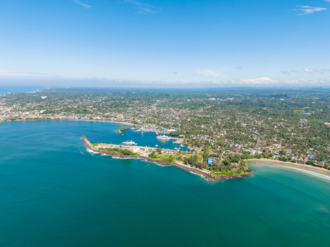 Aerial view of the turquoise waters and coastal landscape of Unawatuna bay featuring the breakwater and lush tropical greenery under a clear blue sky in Unawatuna Sri Lanka. Aerial view of the turquoise waters and coastal landscape of Unawatuna bay featuring the breakwater and lush tropical greenery under a clear blue sky in Unawatuna Sri Lanka.