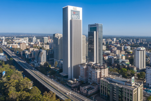 Aerial view of the iconic Britam Tower rising above the Westlands business district with modern skyscrapers a major highway and clear blue skies in Nairobi Nairobi County Kenya. Aerial view of the iconic Britam Tower rising above the Westlands business district with modern skyscrapers a major highway and clear blue skies in Nairobi Nairobi County Kenya.