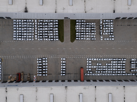 Aerial view of a large logistics facility with rows of parked white cars asphalt surfaces and warehouse buildings in Gdansk Polska. Aerial view of a large logistics facility with rows of parked white cars asphalt surfaces and warehouse buildings in Gdansk Polska.