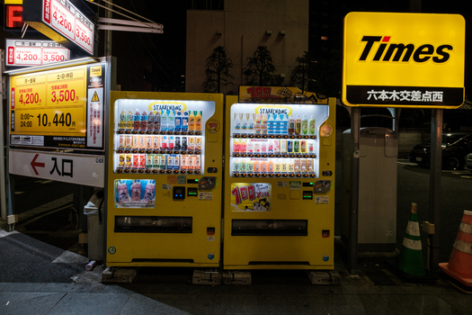 Tokyo Japan 01 October 2025 View of vending machines glowing with soft illumination casting shadows on the dark ground near the Times parking sign. Tokyo Japan 01 October 2025 View of vending machines glowing with soft illumination casting shadows on the dark ground near the Times parking sign.