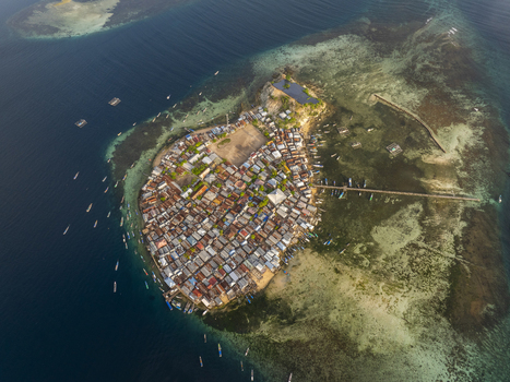 Aerial view of Pulau Mesa a densely populated island village surrounded by turquoise coral reefs and clear blue water in Kecamatan Komodo Nusa Tenggara Timur Indonesia. Aerial view of Pulau Mesa a densely populated island village surrounded by turquoise coral reefs and clear blue water in Kecamatan Komodo Nusa Tenggara Timur Indonesia.