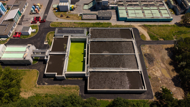 Aerial view of a wastewater treatment plant featuring large aeration tanks with green and dark water industrial infrastructure and surrounding greenery in Milan Lombardy Italy. Aerial view of a wastewater treatment plant featuring large aeration tanks with green and dark water industrial infrastructure and surrounding greenery in Milan Lombardy Italy.