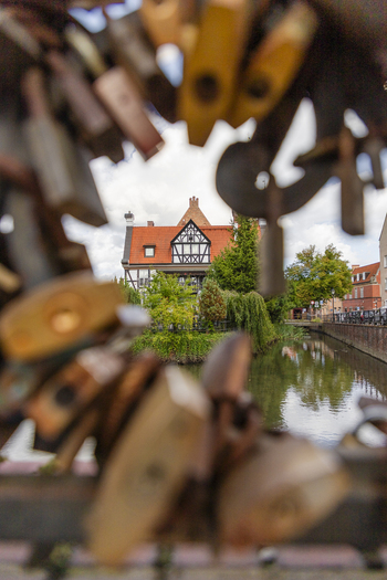 View of a historic half timbered building framed by out of focus padlocks on a bridge railing over a canal in Gdansk Pomeranian Voivodeship Poland. View of a historic half timbered building framed by out of focus padlocks on a bridge railing over a canal in Gdansk Pomeranian Voivodeship Poland.