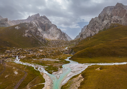 Aerial view of the turquoise glacial river flowing through the dramatic rocky mountains and alpine meadows of the Kol Suu area in At Bashi District Naryn Region Kyrgyzstan. Aerial view of the turquoise glacial river flowing through the dramatic rocky mountains and alpine meadows of the Kol Suu area in At Bashi District Naryn Region Kyrgyzstan.