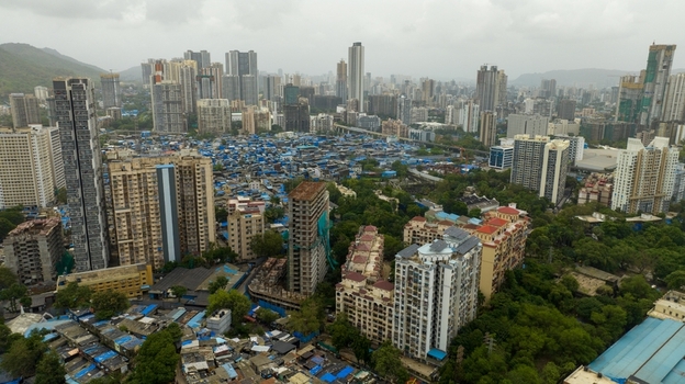 Aerial view of Dharavi Slums surrounded by modern high rise buildings and dense urban infrastructure in Mumbai Maharashtra India. Aerial view of Dharavi Slums surrounded by modern high rise buildings and dense urban infrastructure in Mumbai Maharashtra India.