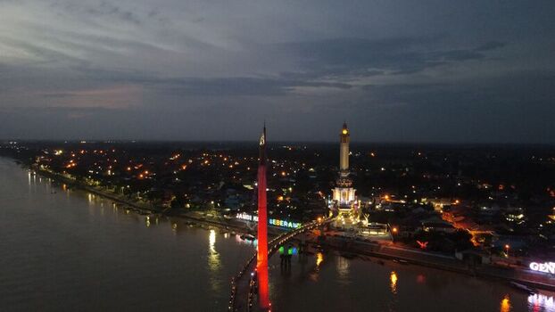Aerial view of the illuminated Gentala Arasy Tower and pedestrian bridge spanning the Batang Hari River at night in Seberang Kota Jambi Indonesia. Aerial view of the illuminated Gentala Arasy Tower and pedestrian bridge spanning the Batang Hari River at night in Seberang Kota Jambi Indonesia.