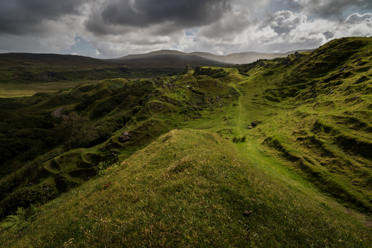 View of the Fairy Glen with rolling green hills and grassy mounds under a dramatic cloudy sky in Wigan England United Kingdom. View of the Fairy Glen with rolling green hills and grassy mounds under a dramatic cloudy sky in Wigan England United Kingdom.