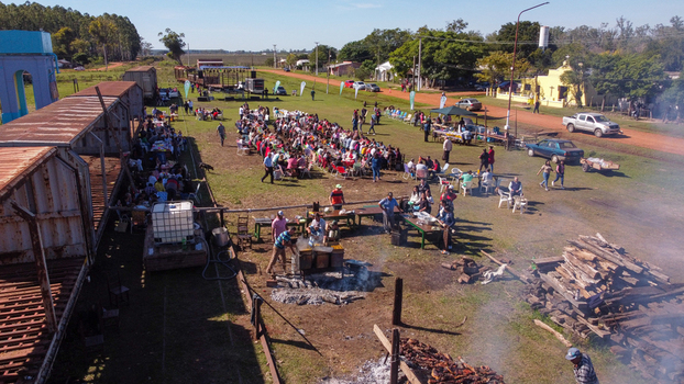 Guaviravi Corrientes Province Argentina 13 May 2023 Aerial view of a community barbecue and locro meal with people at tables in an open field featuring cooking pots and wood fires.