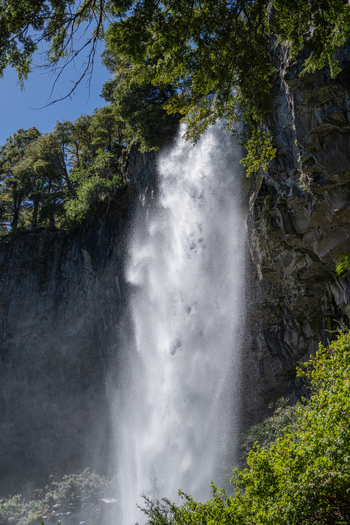 View of Cascada El Saltillo cascading down a rocky cliff face surrounded by lush green trees and foliage in Huiliches Department Neuquen Province Argentina. View of Cascada El Saltillo cascading down a rocky cliff face surrounded by lush green trees and foliage in Huiliches Department Neuquen Province Argentina.