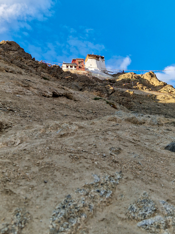 View of Leh Palace perched on a rocky mountain slope under a clear blue sky in Leh Ladakh India.