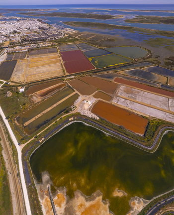 Aerial view of the colorful salt evaporation ponds at Salinas do Grelha with geometric patterns and the coastal landscape of the Ria Formosa in Olhao Faro Portugal. Aerial view of the colorful salt evaporation ponds at Salinas do Grelha with geometric patterns and the coastal landscape of the Ria Formosa in Olhao Faro Portugal.